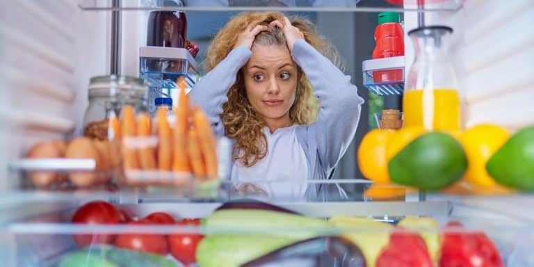 woman looking into the fridge wondering what to eat